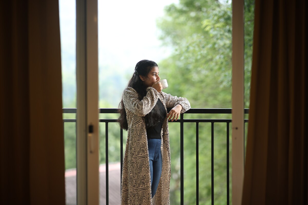 Woman on Balcony Enjoying a Drink with Nature Background