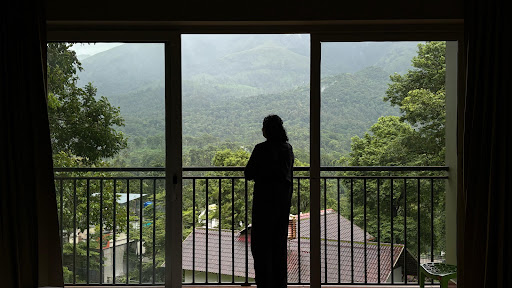 Silhouette of Person Looking Out at Lush Mountain View from Balcony
